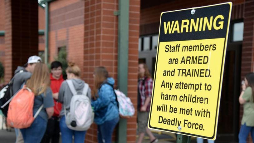 Dublin, Georgia - Students wait for their parents to pick them up at East Laurens Middle-High School on Monday behind a sign that warns visitors of the school that staff members are armed with weapons to protect students. (Jenna Eason for The Atlanta Journal-Constitution)