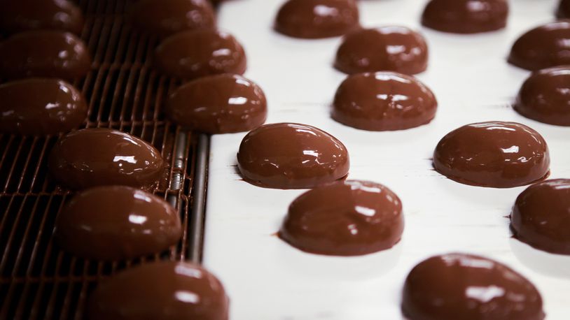 Chocolate covered marshmallows travel down an enrobing belt before they are dunked under a curtain of chocolate for a second time at See’s Candies in Los Angeles. (Bethany Mollenkof/Los Angeles Times/TNS)