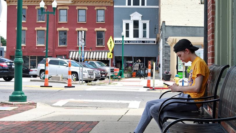 Noah Rogers checks his phone as he sits on a bench along Monument Square in Urbana Tuesday.