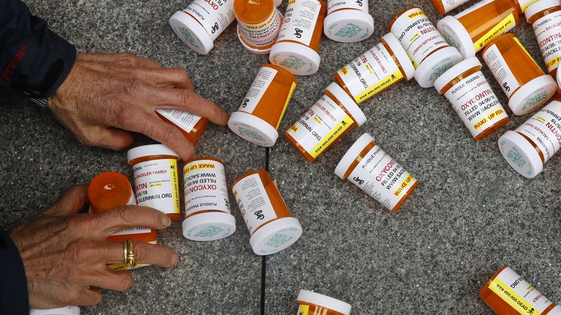 A protester gathers containers that look like OxyContin bottles at an anti-opioid demonstration in front of the U.S. Department of Health and Human Services headquarters in Washington on April 5, 2019. (AP Photo/Patrick Semansky, File)