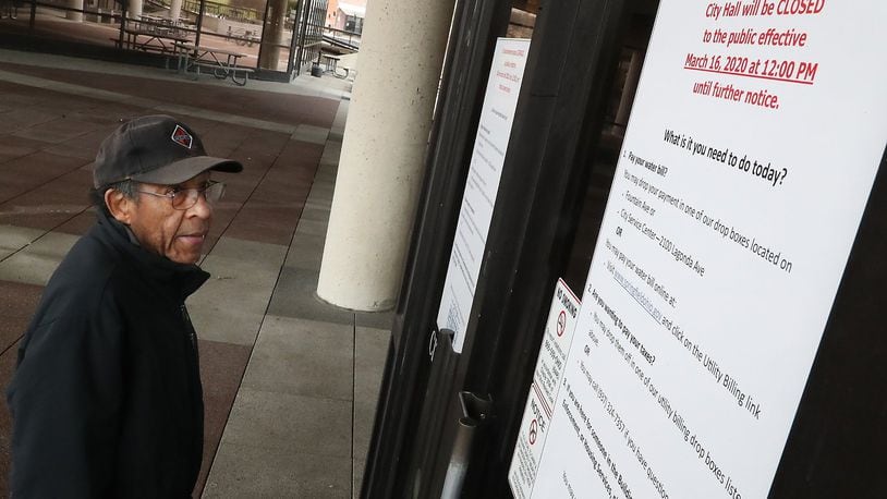 Lewis Hill reads the “Closed” sign on the doors at the Springfield City Hall Monday. Hill said he had come down to City Hall to pay his water bill but was directed to go to a drop box. The City of Springfield offices closed Monday at 12pm due to the health crisis. BILL LACKEY/STAFF