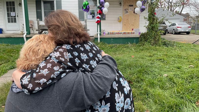 Debby Seymour and Teresa Petersen, loved ones of Gloria Dickinson, embrace in front of the house where Dickinson was found during a vigil on North Douglas Avenue on Monday evening.