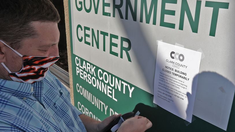 Mike Cooper, Clark County public information officer,  puts up signs announcing the temporary closing of the Clark County government offices at Springview Government Center on Nov. 19. The county will continue with virtual operations "until further notice." BILL LACKEY/STAFF