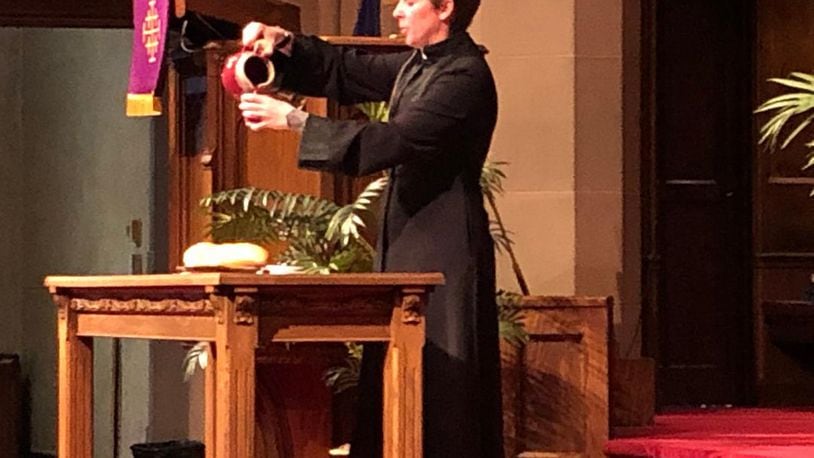 Pastor Darcy Metcalfe of Covenant Presbyterian Church pours a drink symbolic of what was consumed at the Last Supper as part of Maundy Thursday services. She'll lead drive-in Easter Sunday services at Covenant. Photo by Brett Turner
