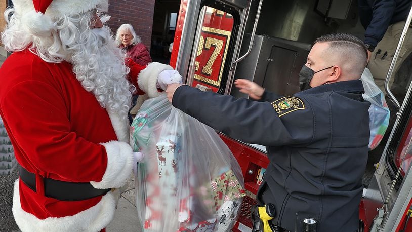 Santa hands off a bag full of gifts to Springfield Police Officer Zach Massie as they fill the Box 27 truck with presents to deliver to Springfield children in need this year. The gifts are all part of Operation Santa, a program in which some of the community's less-fortunate families receive Christmas gifts. The Springfield Police Department's Community Response Team works with local businesses and volunteers to shop, wrap and deliver the gifts for the holiday. BILL LACKEY/STAFF