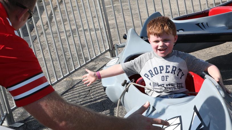 Landon Copeland, 4, smiles as he slaps the hand of his father, Mike, as he passes him on a kiddie ride at the New Carlisle Heritage of Flight Festival Saturday. BILL LACKEY/STAFF