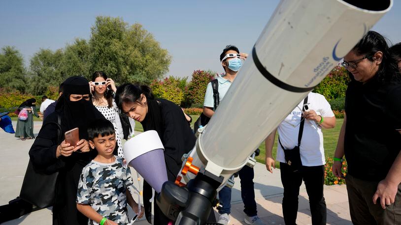 People watch a partial solar eclipse wearing special glasses at the Al Thuraya Astronomy Center, in Dubai, United Arab Emirates, Tuesday, Oct. 25, 2022. (AP Photo/Kamran Jebreili)