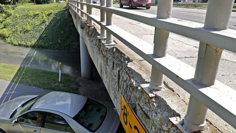 Cars drive over and under the crumbling Bechtle Avenue bridge over Snyder Park Monday. Bill Lackey/Staff