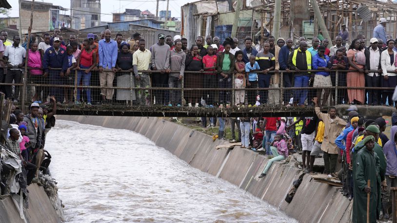 People stand on a bridge, as they watch houses in riparian land being demolished in the Mukuru area of Nairobi, Tuesday, May. 7, 2024. The government ordered the demolition of structures and buildings, illegally constructed along riparian areas. Kenya, along with other parts of East Africa, has been overwhelmed by flooding. (AP Photo/Brian Inganga)