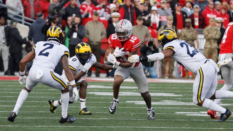 Ohio State receiver Xavier Johnson, center, tries to run between Michigan defenders during the second half of an NCAA college football game on Saturday, Nov. 26, 2022, in Columbus, Ohio. (AP Photo/Jay LaPrete)