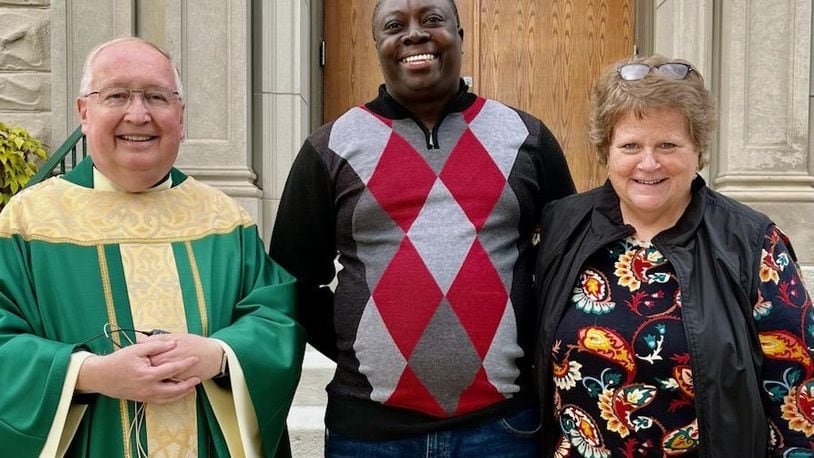 Rev. John MacQuarrie, Patrick Joseph and Casey Rollins stand in front of St. Bernard Catholic Church in Springfield. MacQuarrie is pastor of Springfield's Catholic churches, Joseph is an immigrant from Haiti living in Springfield who volunteers with St. Vincent de Paul in Springfield and Rollins is board president and executive director at St. Vincent de Paul. STAFF
