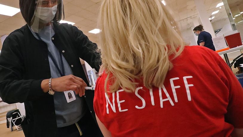 A member of the Northeastern High School staff gets the COVID-19 vaccine from nurse Salimah Berrien in the Clark County vaccine distribution center at the Upper Valley Mall Wednesday. BILL LACKEY/STAFF