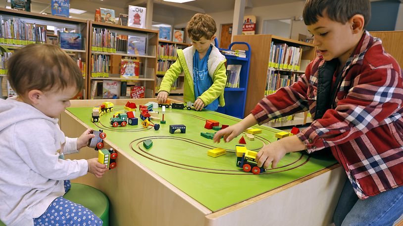 P.J. Fields, left, and her brothers, Elliott, center, and Logan play with the trains in the newly renovated Youth Services Department at the New Carlisle Public Library Monday, Feb. 6, 2023. The library has spent the past few weeks working on the project, which includes replacing the furnature and frooring as well as a dedicated area for teens, an adaptable space for story time and other programs and a circulation desk in the Youth Services area. It is the library's first remodel in nearly 20 years. BILL LACKEY/STAFF