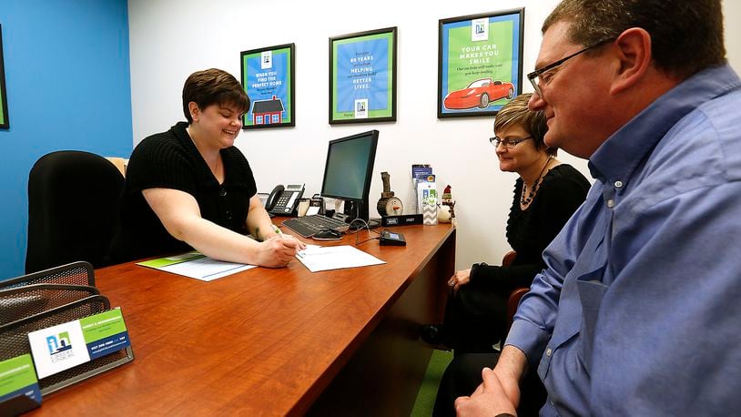 An IH Credit Union employee about checking accounts with a customer in March, 2016. Bill Lackey/STAFF