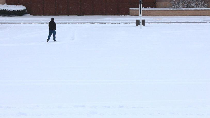 A man walks through a snow covered parking lot in Huber Heights Sunday morning. BILL LACKEY/STAFF (edited)