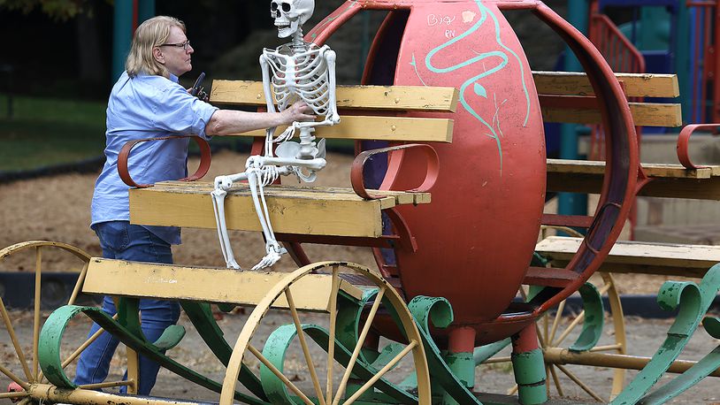 Sharon Thornton places her skeleton named "Hank" in the driver's seat of the pumpkin carriage at the Veterans Park playground Thursday, Sept. 28, 2023. Every year around Halloween, Sharon says she brings "Hank" out and takes pictures of him in random places around Springfield for the amusement of her family and friends. BILL LACKEY/STAFF