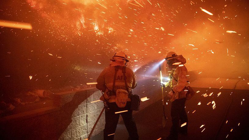 In this Thursday, Oct. 10, 2019 photo, embers from the Saddleridge fire blow by firefighters in Sylmar, Calif.