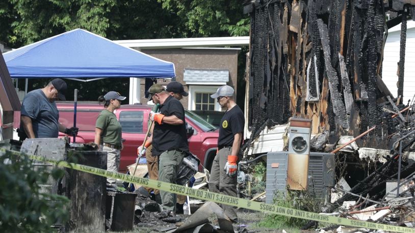 Investigators from BCI continue to sift through the remains of the burned out trailer at Harmony Estates Monday morning. BILL LACKEY/STAFF