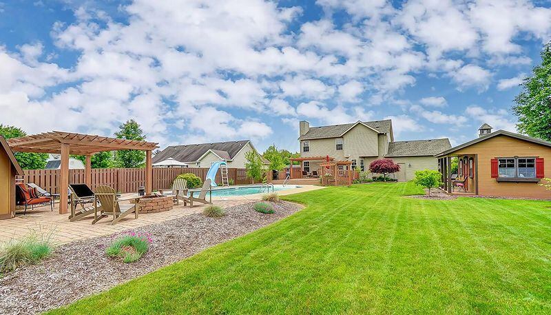 The backyard is fully fenced and includes composite decks, unistone and stamped concrete patios, an inground pool with a slide, three wooden pergolas, one of which has a swing, a shed and a round brick fireplace.  CONTRIBUTED PHOTO