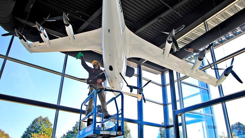 Owen Flannery, an employee with the city of Springfield, cleans the electric vertical take off and landing aircraft (eVTOL) that hangs in the lobby of the new National Advanced Air Mobility Center of Excellence at Springfield-Beckley Municipal Airport on Thursday, Sept. 14, 2023. BILL LACKEY/STAFF