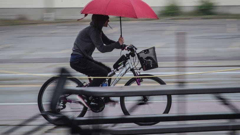A cyclist speeds down East Fifth St. Thursday June 3, 2021 dodging rain and cars at the same time. JIM NOELKER/STAFF