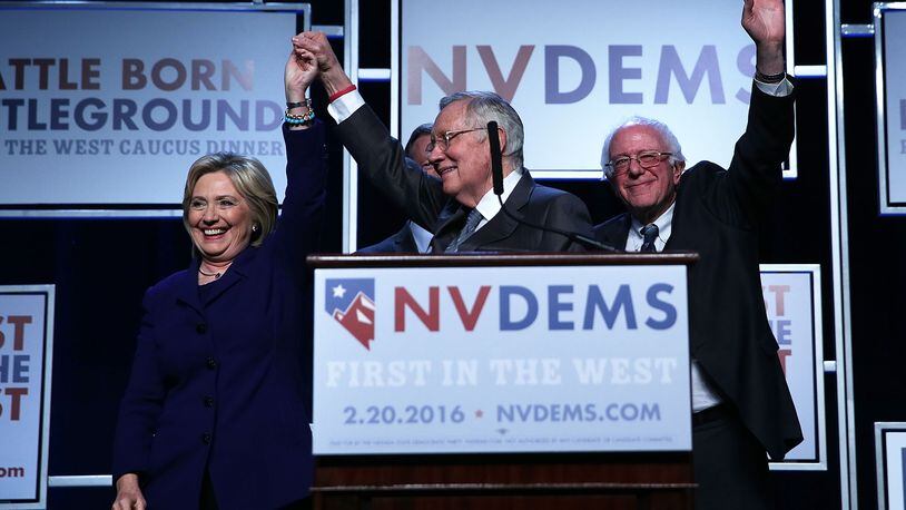 Democratic Presidential candidates Hillary Clinton (L) and Sen. Bernie Sanders (I-VT) (R) on stage with Senate Minority Leader Harry Reid (D-NV) (2nd L) prior to the Battle Born/Battleground First in the West Caucus Dinner at the MGM Grand January 6, 2016 in Las Vegas, Nevada.