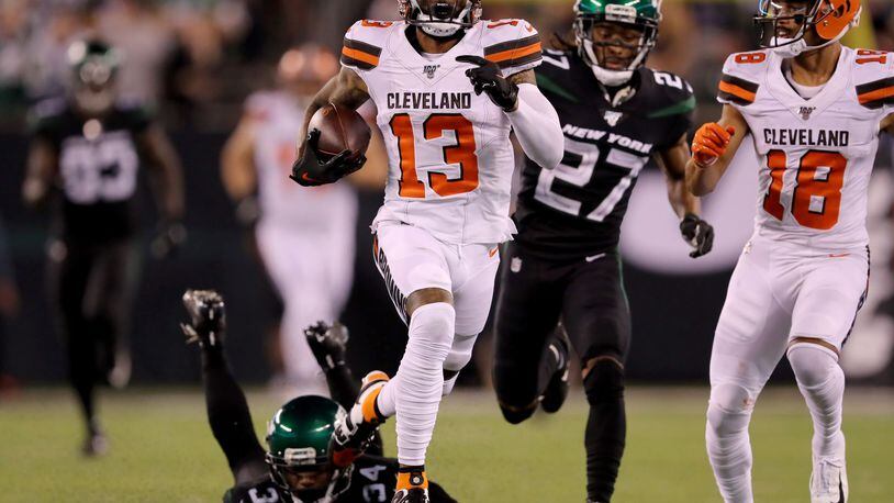 EAST RUTHERFORD, NEW JERSEY - SEPTEMBER 16: Odell Beckham Jr. #13 of the Cleveland Browns breaks free from Brian Poole #34 and Darryl Roberts #27 of the New York Jets to run the ball 89 yards in for the touchdown in the third quarter at MetLife Stadium on September 16, 2019 in East Rutherford, New Jersey. (Photo by Elsa/Getty Images)