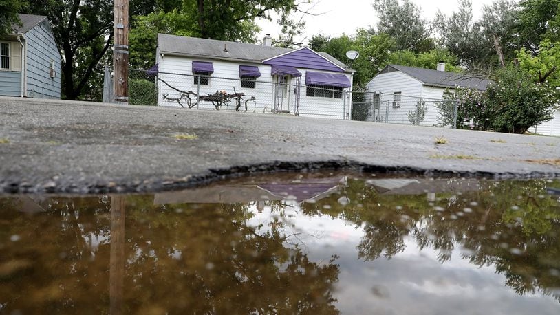 A rain puddle reflects the neighborhood along Russell Avenue where Gary Cameron, 21 of Springfield was shot and killed early Friday morning. Bill Lackey/Staff