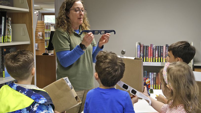 Penny Dunbar, from National Trail Parks and Recreation District, explains to a group of children how important it is to wear eclipse glasses Wednesday, April 3, 2024 during a program called Solar Shadow at the New Carlisle Public Library. BILL LACKEY/STAFF