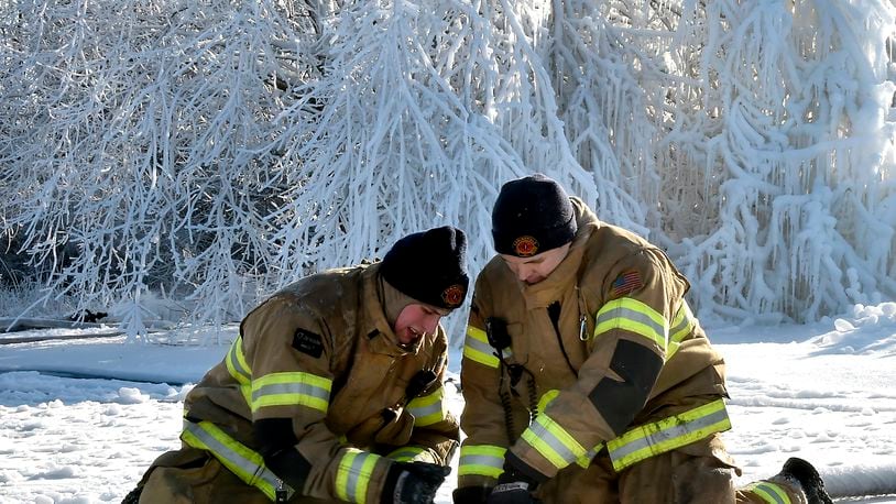 Members of the Springfield Fire Division try to break their fire hoses apart after they were coated with ice Wednesday morning following an overnight five alarm industrial fire in the 200 block of Monroe Street. Bill Lackey/Staff