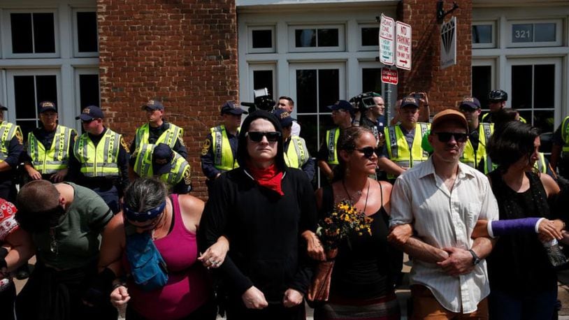 Members of the Charlottesville community and protest groups locked arms in front of police on Aug. 12. The next day, the organizer of a Unite the Right rally was punched by a man when he attempted to make a speech.