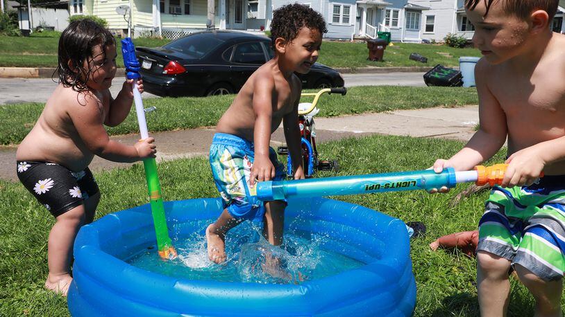 A kiddy pool full of water made the hot weather a little more bearable for cousins Aurora Lytle, left, Xavier Burrows, center, and Ross Niemeyer as they play in the pool and with water guns in their front yard along East Northern Avenue in Springfield. BILL LACKEY/STAFF