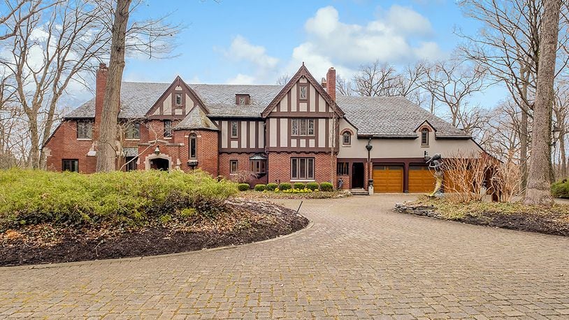 This Tudor-style home features almost 7,000 sq. ft. of living space with 6 bedrooms and a walk-out lower level. A circular brick driveway winds through woods on the 5.6-acre lot to the 3-car garage with wood doors. CONTRIBUTED PHOTO