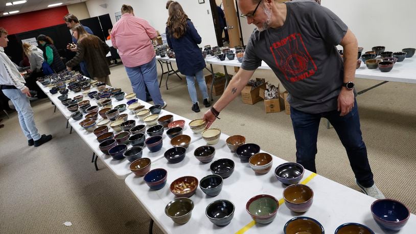 Scott Deeley, professor of art at Wittenberg University, checks out the bowls for sale Thursday, March 23, 2023 at the Empty Bowls fundraiser at the university. During the 28th annual Empty Bowls event, hosted by the Wittenberg Art Department in conjunction with Second Harvest Food Bank of Clark, Champaign and Logan Counties, attendees got to choose one of 1,000 unique bowls created locally for $20 and enjoy one of nine soups and bread in the company of other community members. The money from the event helped Second Harvest Food Bank food hungry residence in the community. BILL LACKEY/STAFF