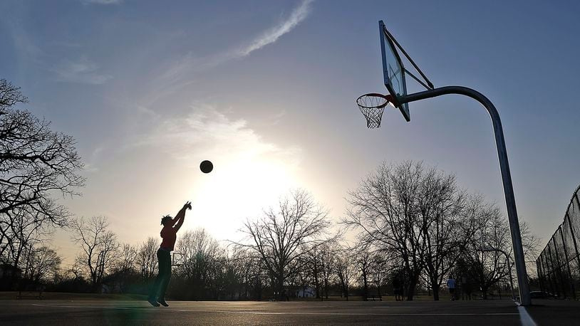 Ian Sheffield, 12, shoots baskets on the courts at Davey Moore Park Wednesday evening as the sun goes down. Black-led groups are working together to increase the number of parks and green space areas available in South Springfield. BILL LACKEY/STAFF