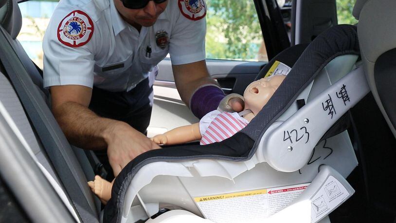 A City of Miami Fire Rescue member removes a test dummy used for a rescue demonstration on the methods to save the life of an infant or pet in case of emergency, during a news conference at the Florida Highway Patrol headquarters in Doral, Fla., on June 22. (Sebastian Ballestas/Miami Herald/TNS)