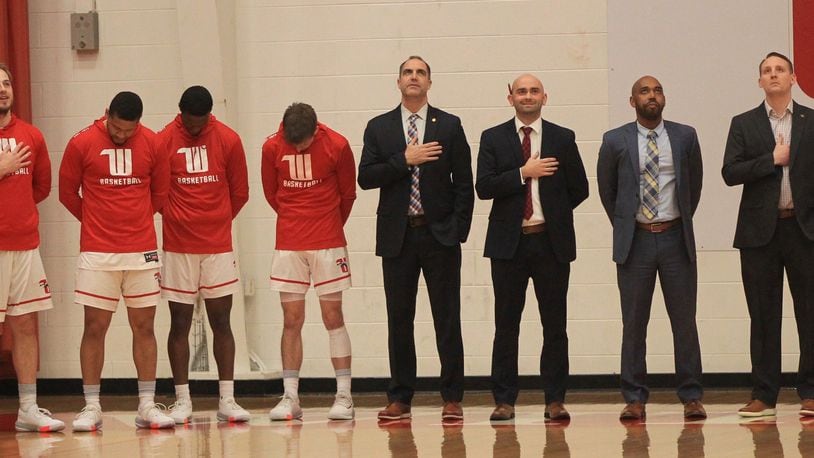 Wittenberg players and coaches, including head coach Matt Croci, center, stand for the national anthem before a game against Denison on Wednesday, Feb. 5, 2020, at Pam Evans Smith Arena in Springfield. David Jablonski/Staff