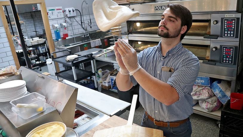 Ryan Thomas, an employee of Crust & Company in the Springfield COhatch, makes a pizza for a customer Thursday, June 16, 2022. BILL LACKEY/STAFF