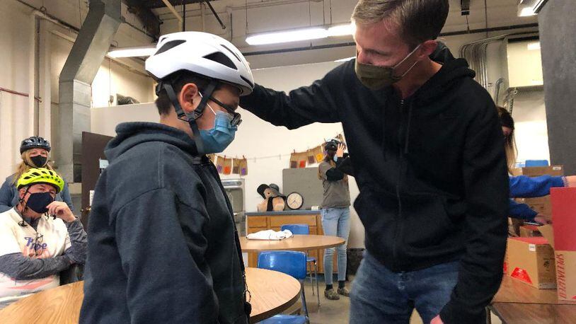 Scott King, president of Bike Greater Springfield, adjusts a new bicycling helmet for Project Jericho member Gilberto Marquez prior to a bike ride on May 6. The organizations will collaborate for a new mural on the bike path on Springfield’s south side this month. Photo by Brett Turner