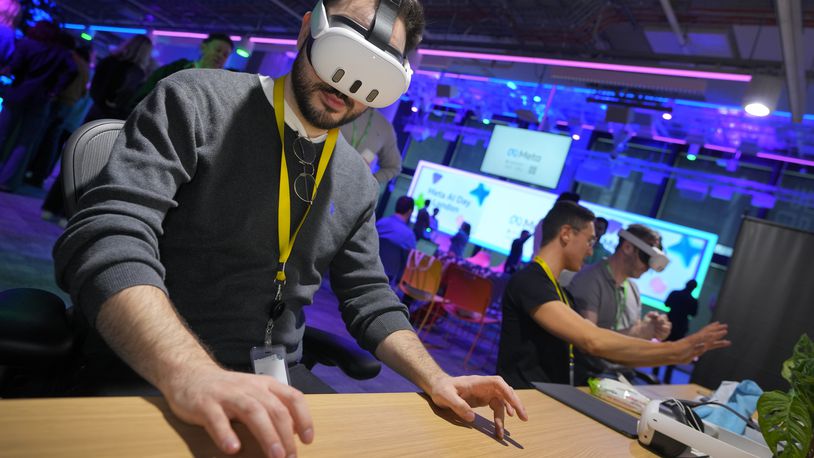 A visitor tries out a Meta Quest 3 headset to for a mixed reality piano playing experience at the Meta AI Day in London, Tuesday, April 9, 2024. Meta's prominent executives on the topic of AI discussed the advancements Meta has made in powering innovation, leading cutting-edge research, and developing new tools for creativity and connection. (AP Photo/Kirsty Wigglesworth)