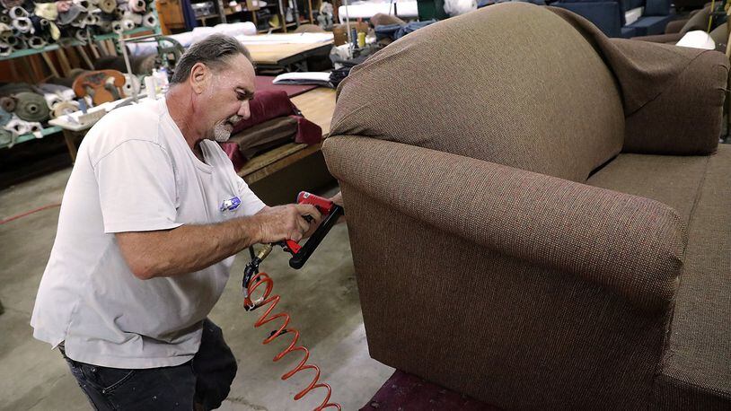Richard Donaldson upholsters a love seat in the Jim Miller Furniture workshop Wednesday at their new location at 2960 Dayton Road. BILL LACKEY/STAFF
