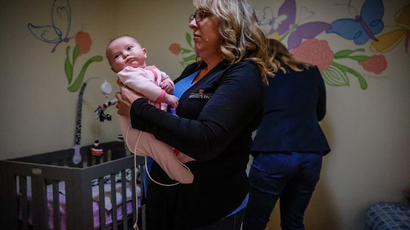 Jill Kingston holds an infant at Brigid's Path in Kettering. Kingston is the founder and president of the facility, which has helped approximately 250 newborns for nearly six years. JIM NOELKER/STAFF