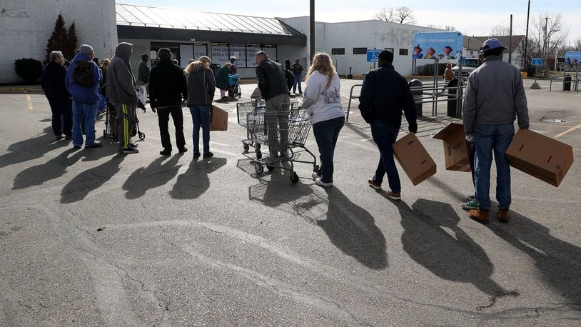 People wait in line earlier this month in the Kroger parking lot on South Limestone for the Second Harvest Food Bank’s Mobile Food Pantry. BILL LACKEY/STAFF