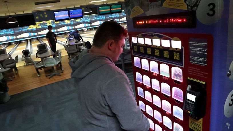 Brandon Oty looks over the Ohio Lottery instant games in a kiosk at Victory Lanes bowling alley in Springfield. BILL LACKEY/STAFF