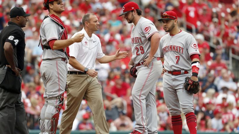 Cincinnati Reds starting pitcher Brandon Finnegan (29) is checked on by a trainer as teammates Devin Mesoraco, left, and Eugenio Suarez (7) stand by during the fourth inning of a baseball game against the St. Louis Cardinals Monday, June 26, 2017, in St. Louis. Finnegan left the game. (AP Photo/Jeff Roberson)
