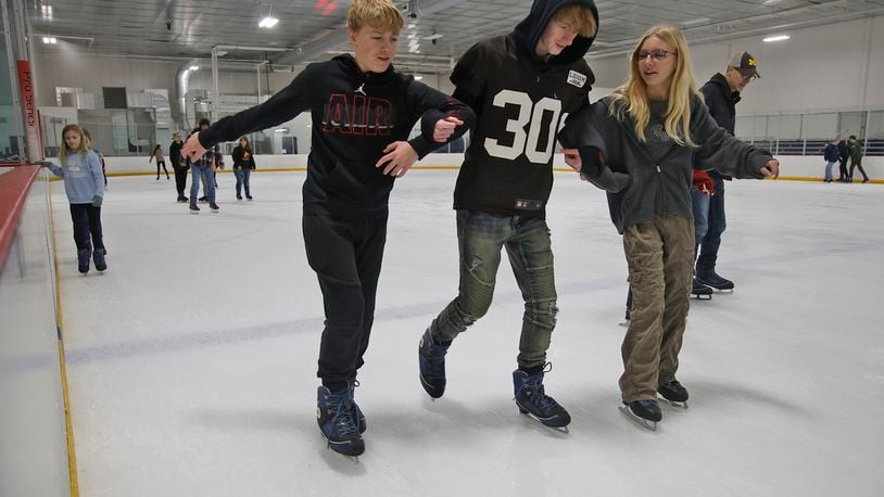 Three friends, from left, Tarrence Chapman, Christian Cloud and Kyndall Brown link arms for stability as they work their way aroung the ice Friday, Dec. 29, 2023 at National Trail Parks and Recreation District's Chiller Ice Skating Rink. BILL LACKEY/STAFF