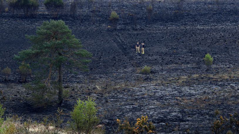 Firefighters check the area after a fire at Ashdown Forest, southern England, Monday April 29, 2019. Fire services attended the scene Sunday evening to tackle the blaze.