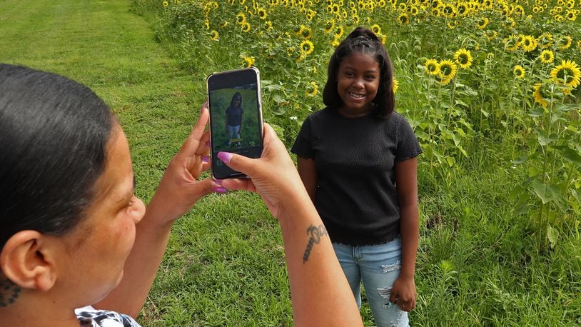 Janae Watkins takes Aaliyah Moss's picture in front of the sunflower field Friday. BILL LACKEY/STAFF