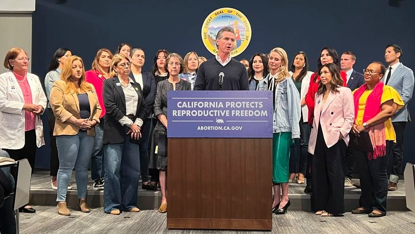 Joined by the state Legislative Women's Caucus and advocates, California Gov. Gavin Newsom, center, speaks during a news conference, Wednesday, April 24, 2024, in Sacramento, Calif., to announce legislation that would help Arizona women access abortions. The proposal would circumvent a ban on nearly all abortions in Arizona by allowing Arizona doctors to give their patients abortions in California. (AP Photo/Sophie Austin)