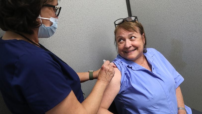 Gabriele Leventhal talks to Becky Schwaiger, an RN at the Clark County Combined Health District, as she gets a COVID vaccine shot in July. BILL LACKEY/STAFF